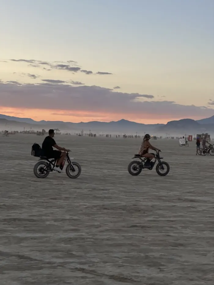 Ysabelle and Jordan riding across the playa at sunset on their second burn