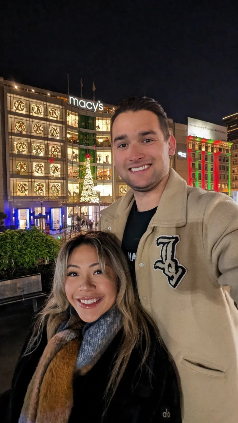 Ysabelle and Jordan in Union Square at Christmas, with the tree and Macy&rsquo;s lit up behind them