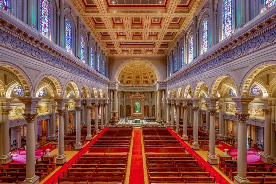 The nave of St. Ignatius Church, with red-carpeted aisles, columns and stained glass